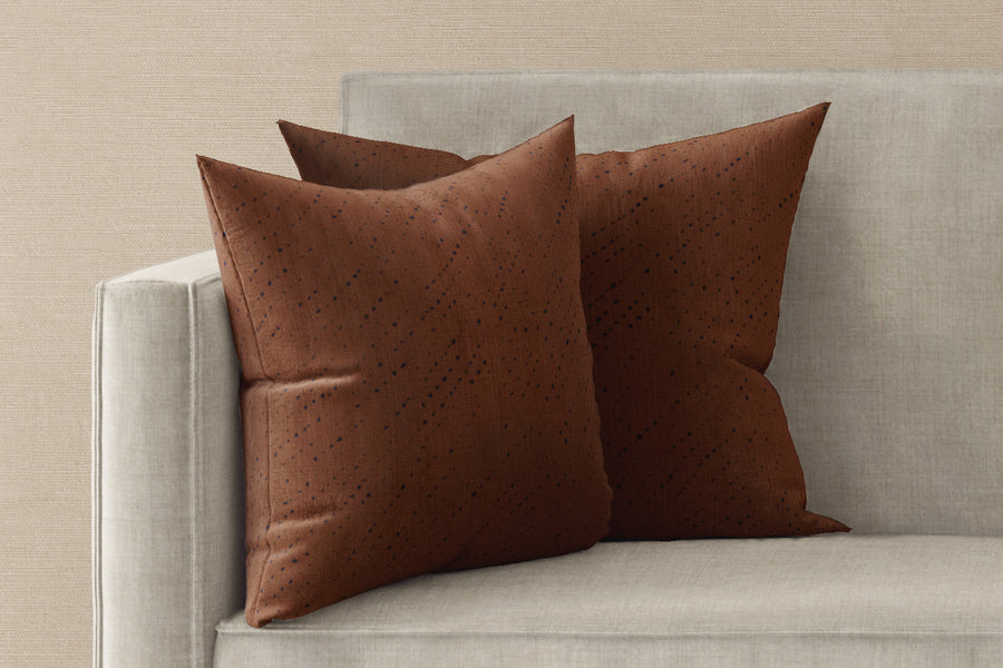 Two 20” x 20” 100% linen reversible staccato nero shibori pillows in russet brown on a sofa