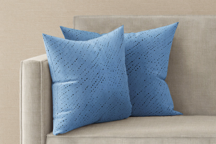 Two 20” x 20” 100% linen reversible staccato nero shibori pillows in sky blue on a sofa