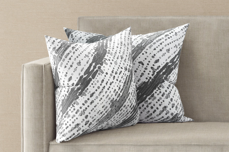 Two 20” x 20” 100% linen reversible glissando shibori pillows in storm grey on a sofa