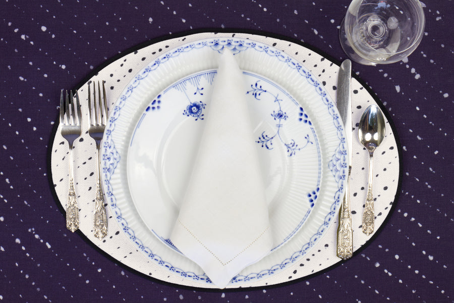 Place setting with 100% linen staccato nero shibori alabaster white placemat on sapphire linen with blue & white plates