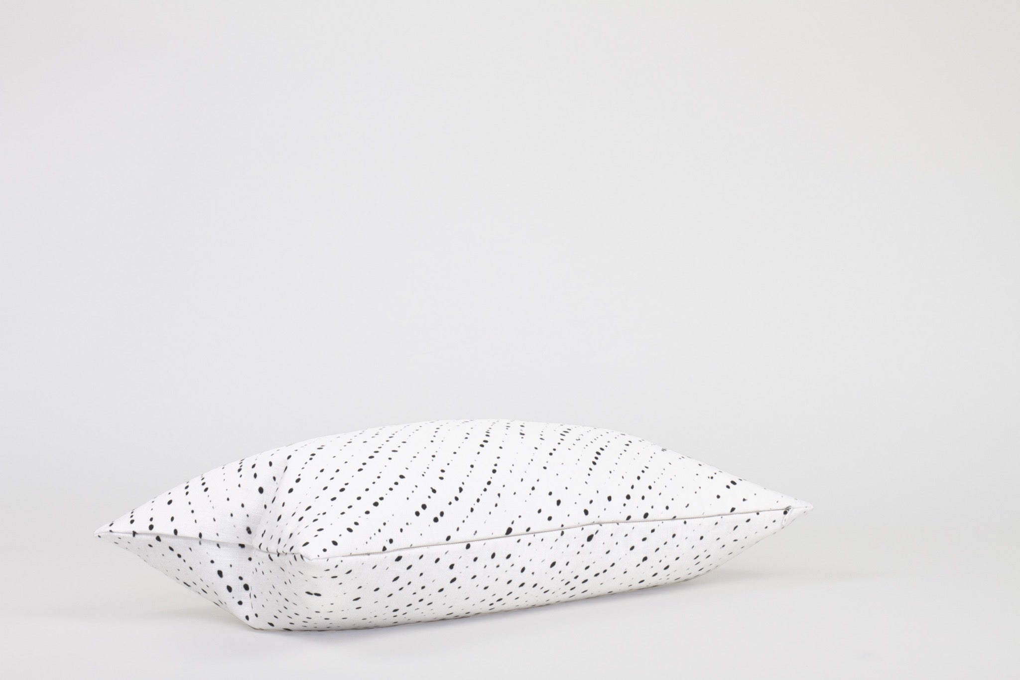 Side view 12” x 20” 100% linen staccato nero shibori pillow in alabaster white with hidden zipper