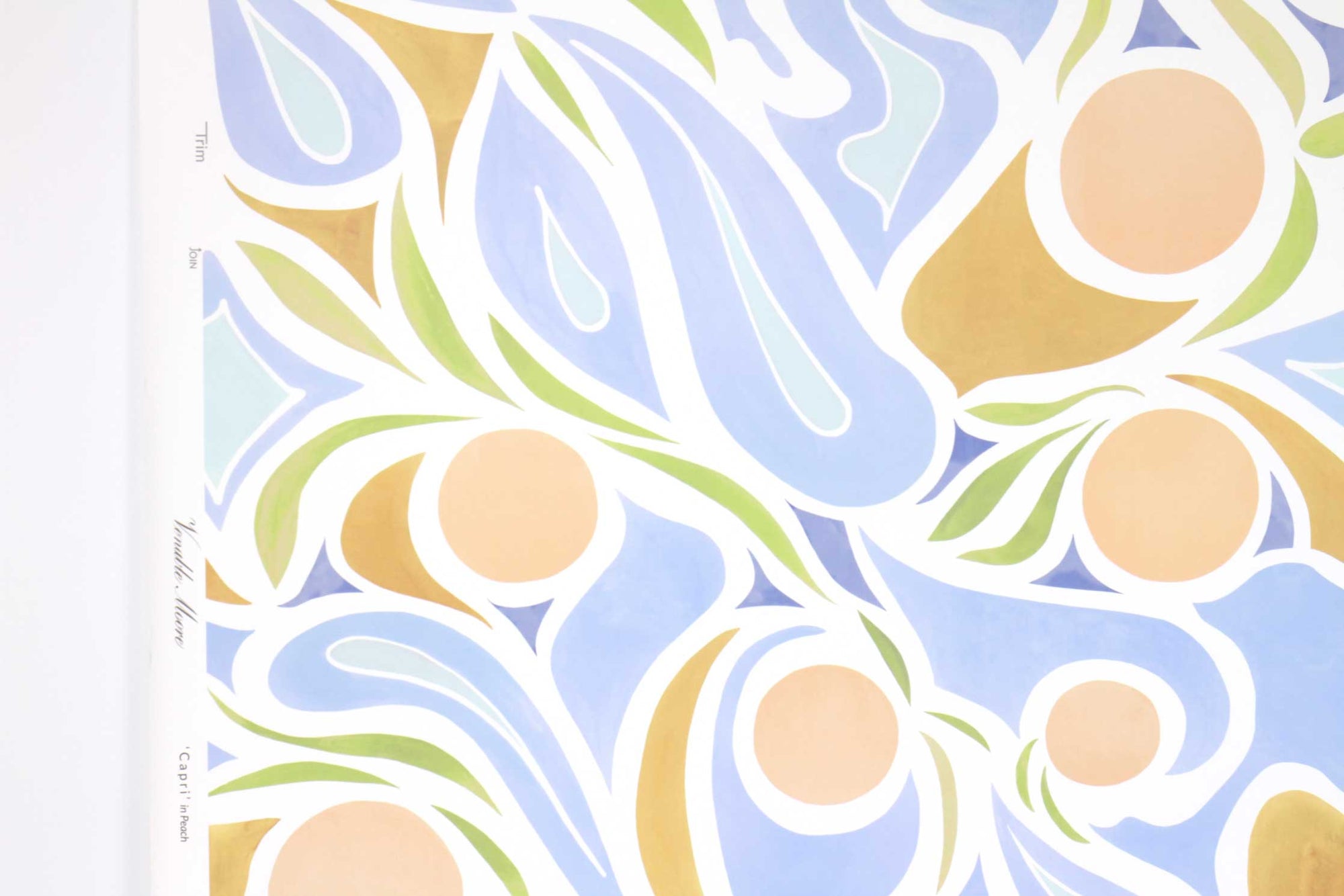 Up close view of Venable Moore ‘Capri’ Pastel Peach Pink, Blue, and Tan FSC Certified Clay Coated wallpaper roll against a white wall