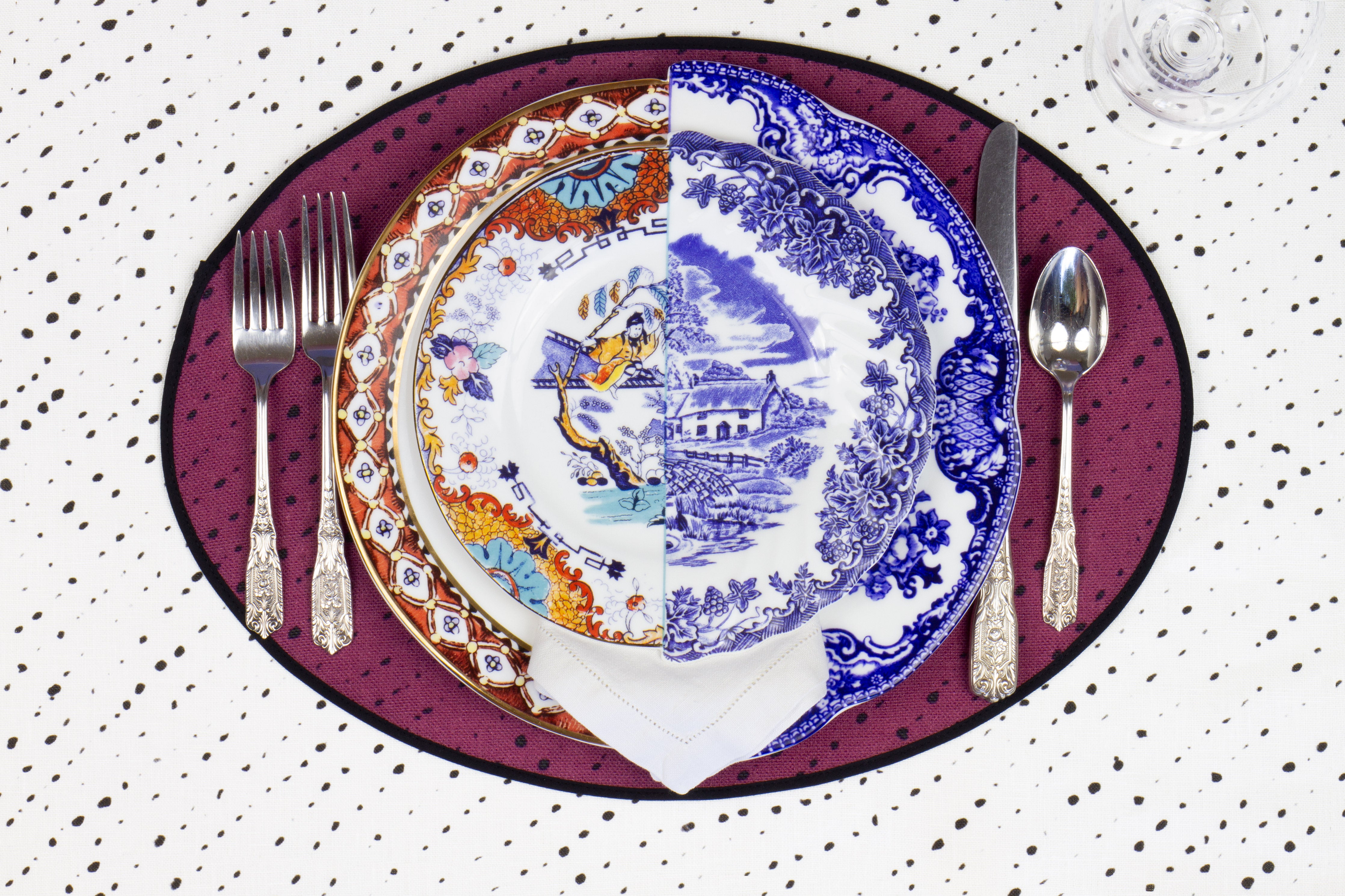 Place setting with 100% linen staccato nero shibori cerise pink placemat on alabaster shibori with colored plates