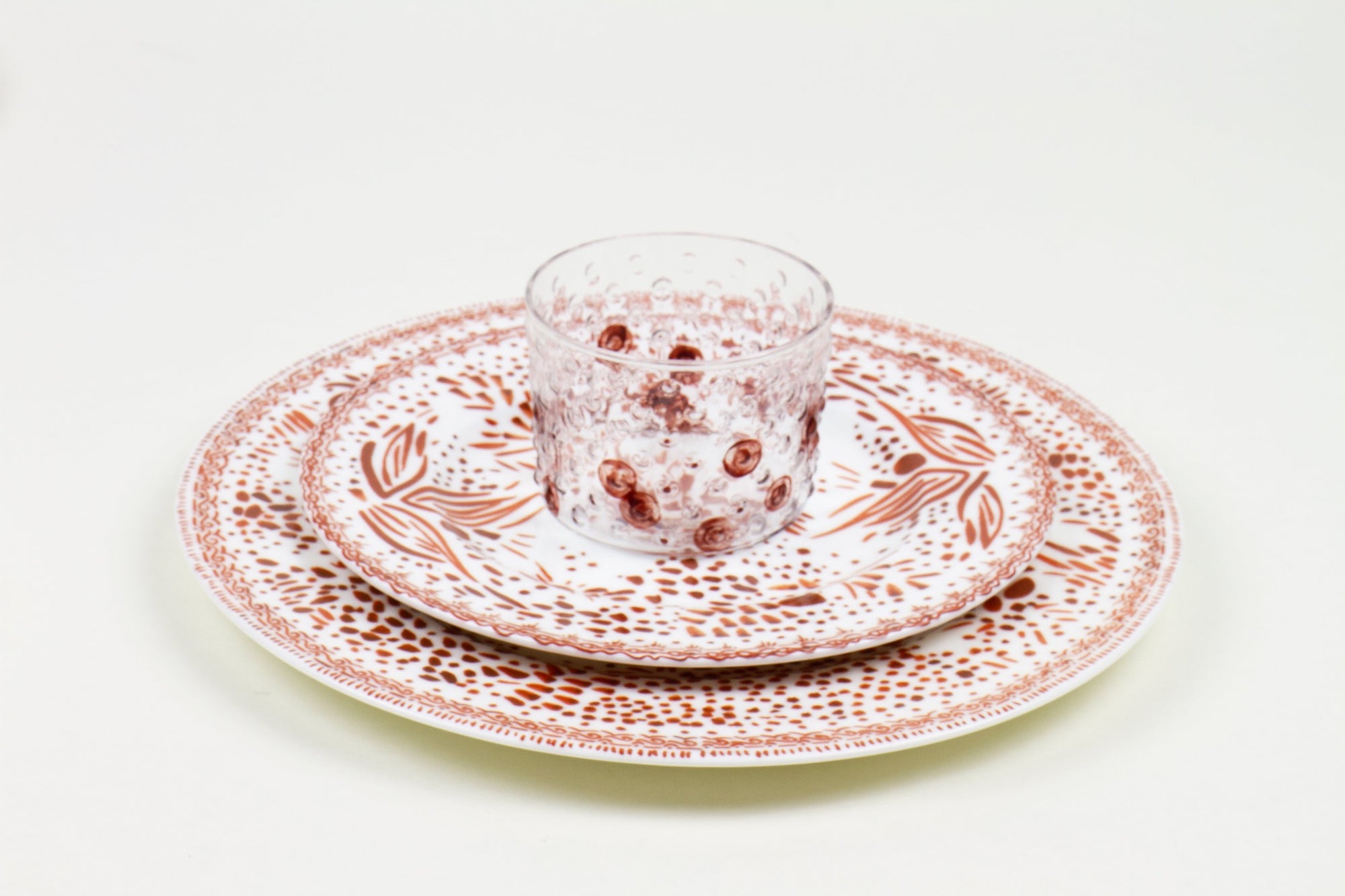 Place setting of hand-painted coffee glass stacked on chestnut mosaic garden salad and dinner porcelain plates