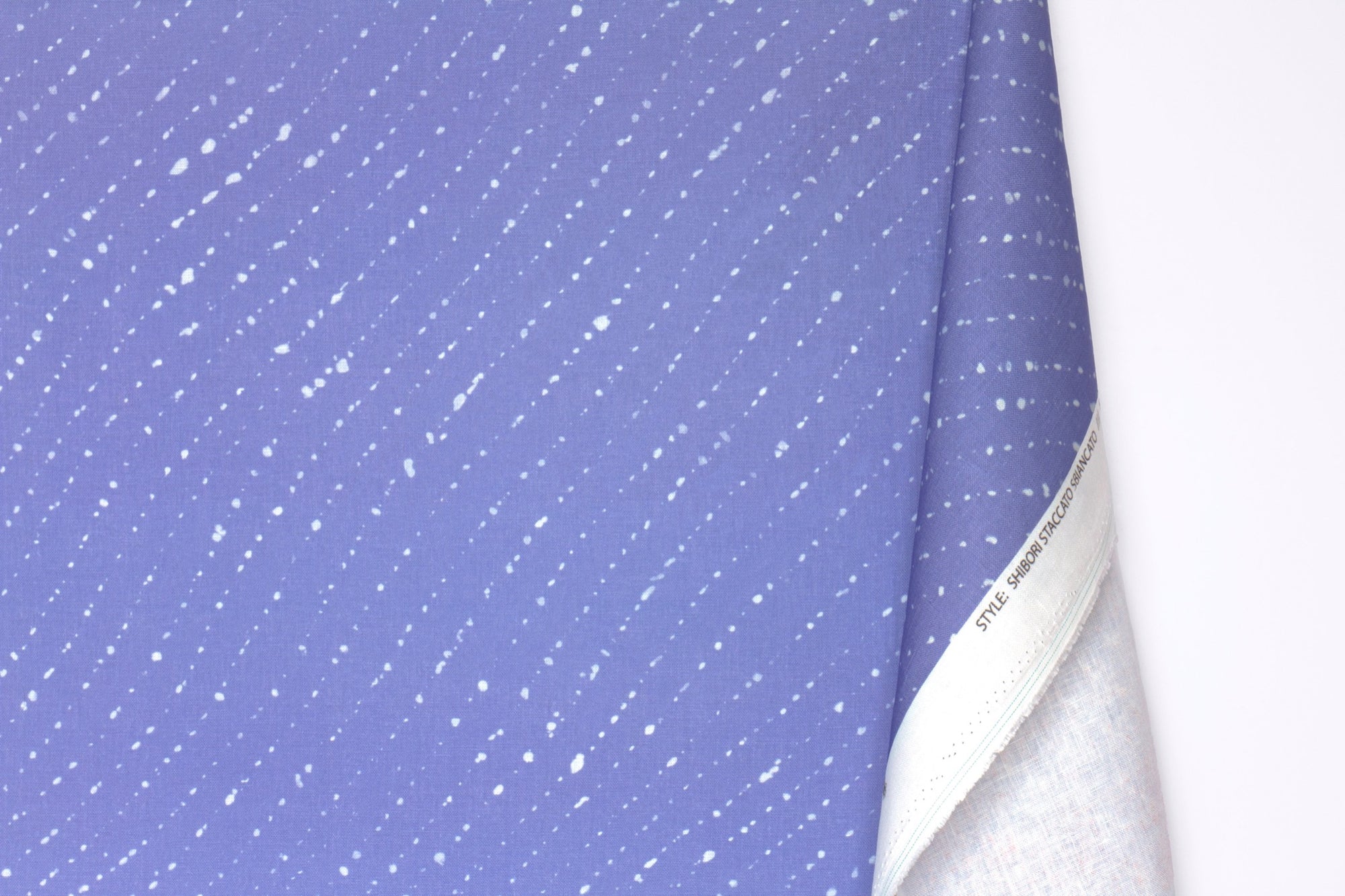 Venable moore 100% european linen staccato sbiancato shibori fabric by the yard with long fold in clear cornflower blue against a white background