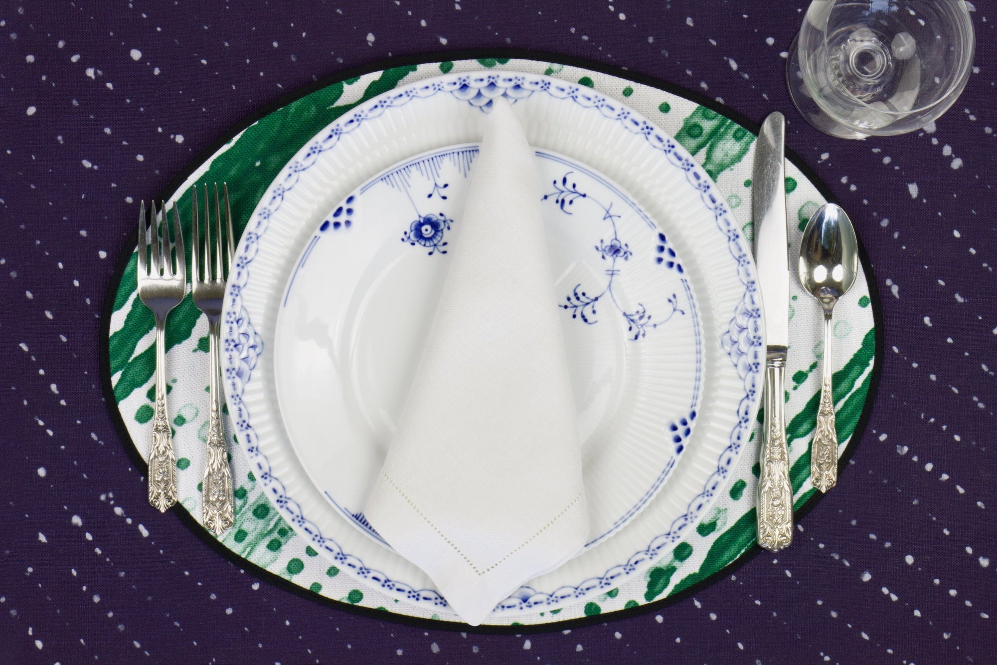 Place setting with 100% linen glissando shibori emerald green placemat on sapphire linen with blue &amp; white plates