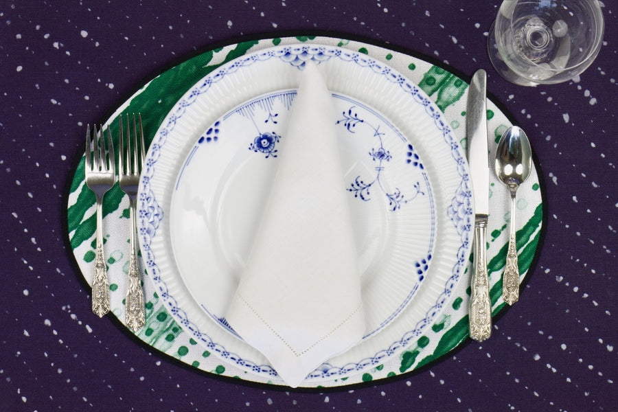 Place setting with 100% linen glissando shibori emerald green placemat on sapphire linen with blue & white plates