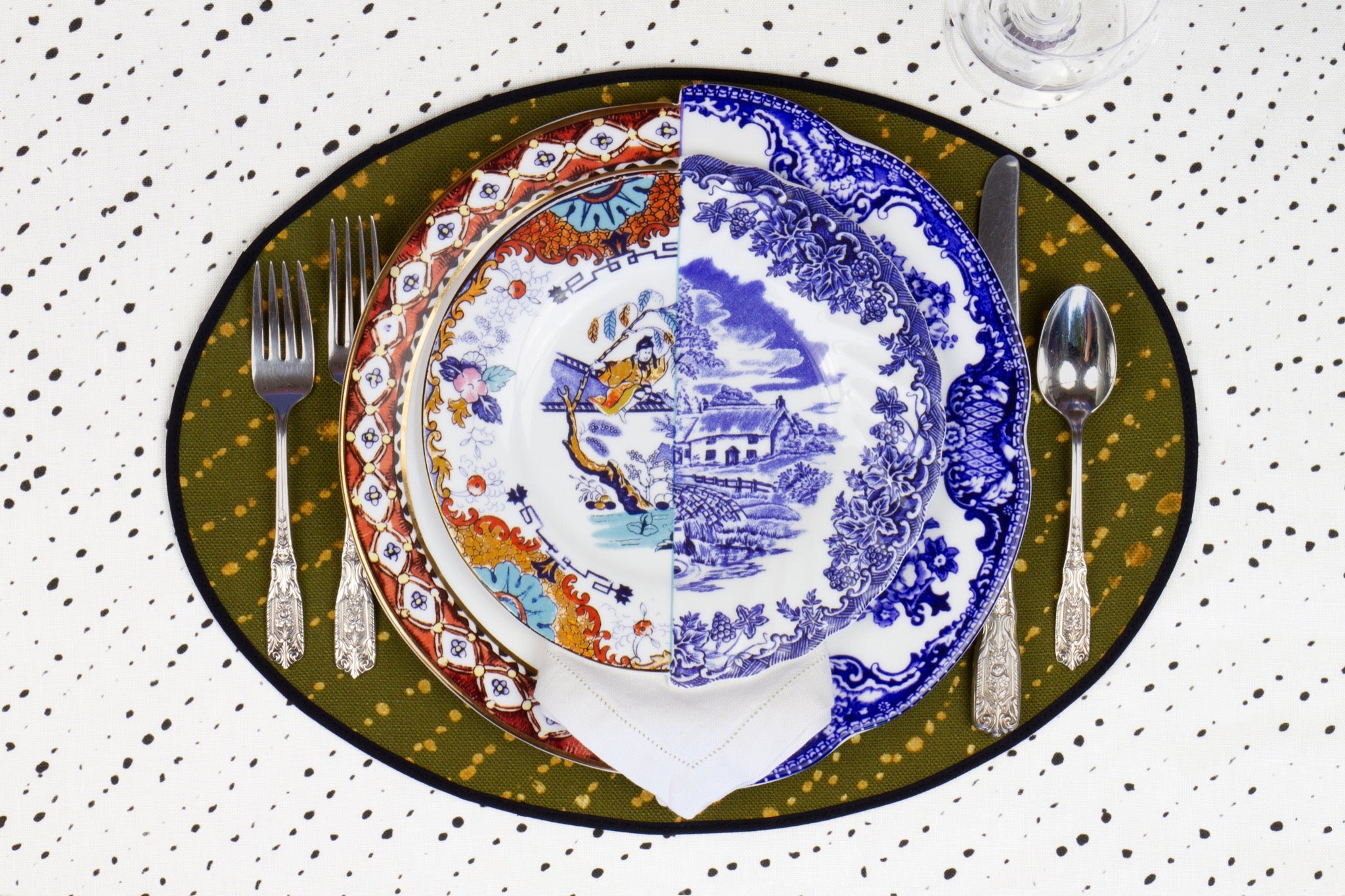 Place setting with 100% linen staccato decolorato shibori fern green placemat on alabaster shibori with colored plates