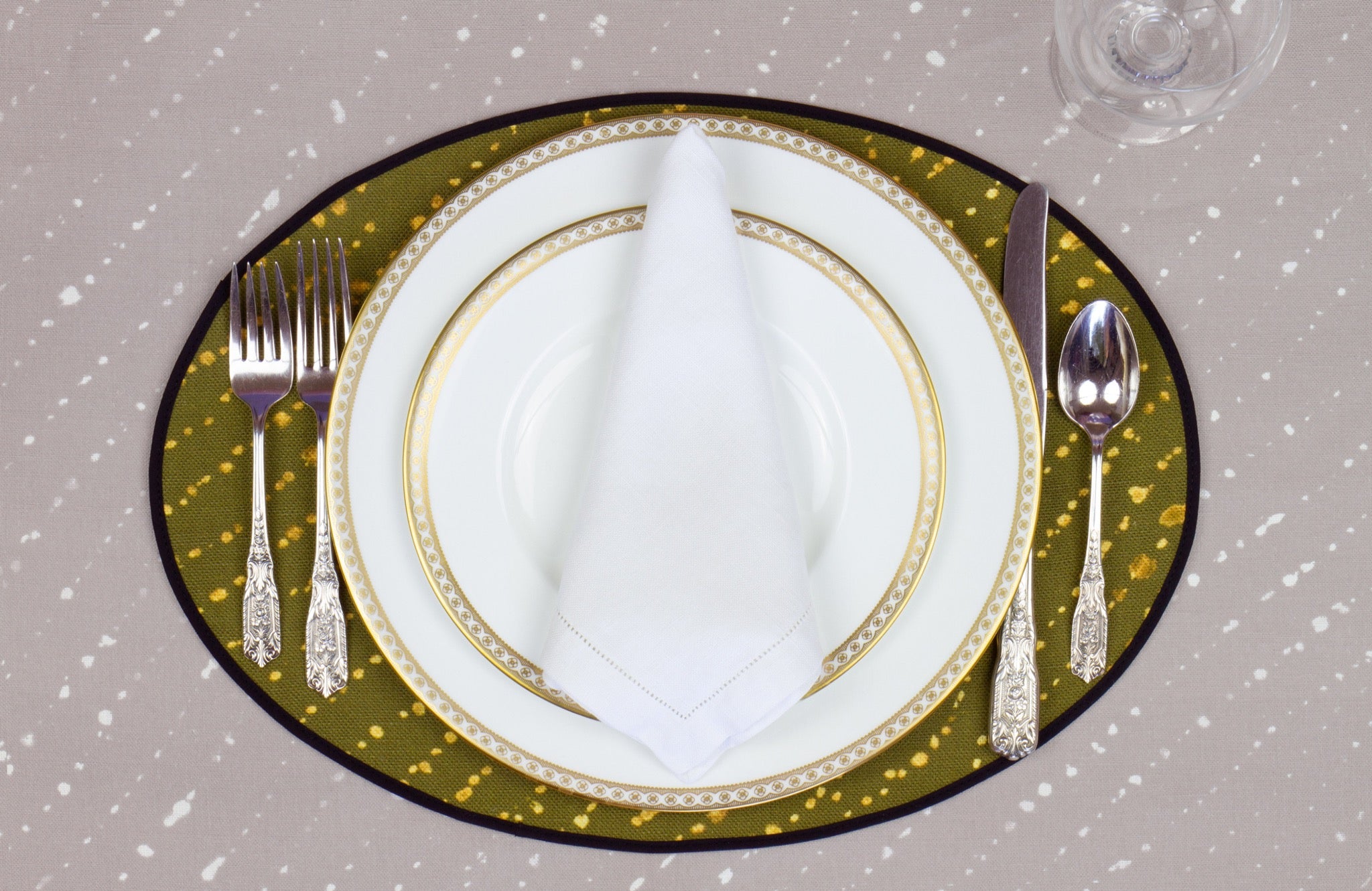 Place setting with 100% linen staccato decolorato shibori fern green placemat on flax shibori linen with white plates