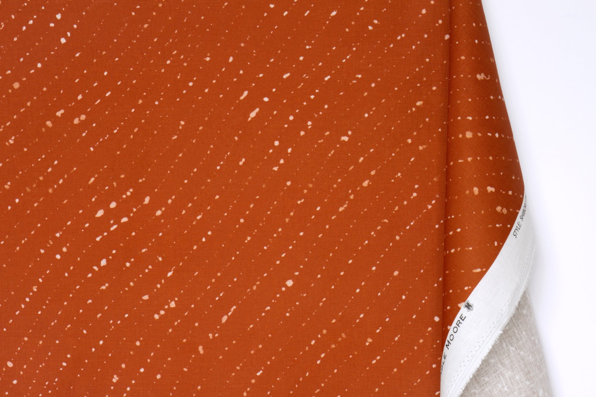 Venable moore 100% european linen staccato sbiancato shibori fabric by the yard with long fold in earthy ginger orange against a white background