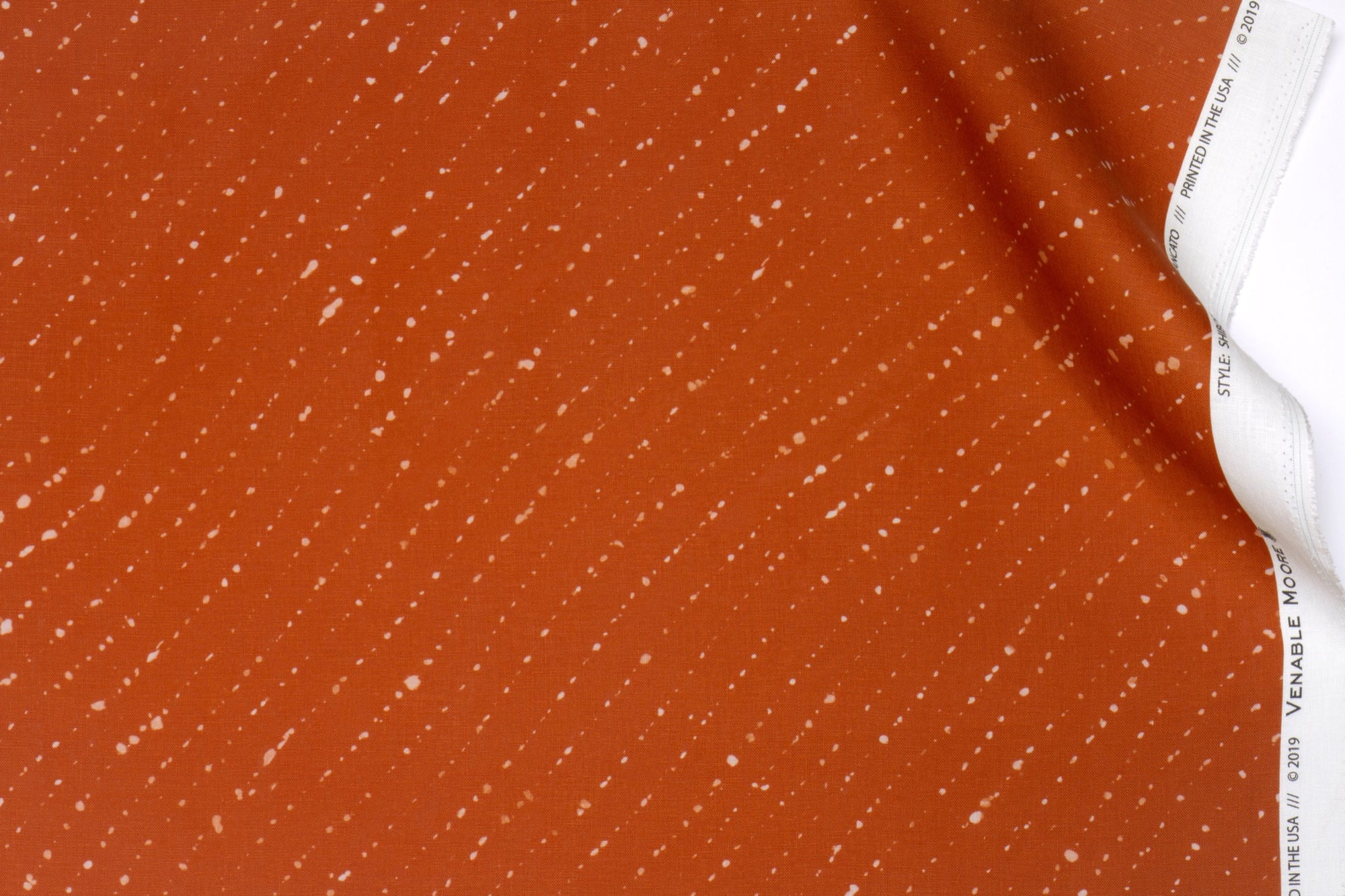 Venable moore 100% european linen staccato sbiancato shibori fabric by the yard in earthy ginger orange with top fold against white background