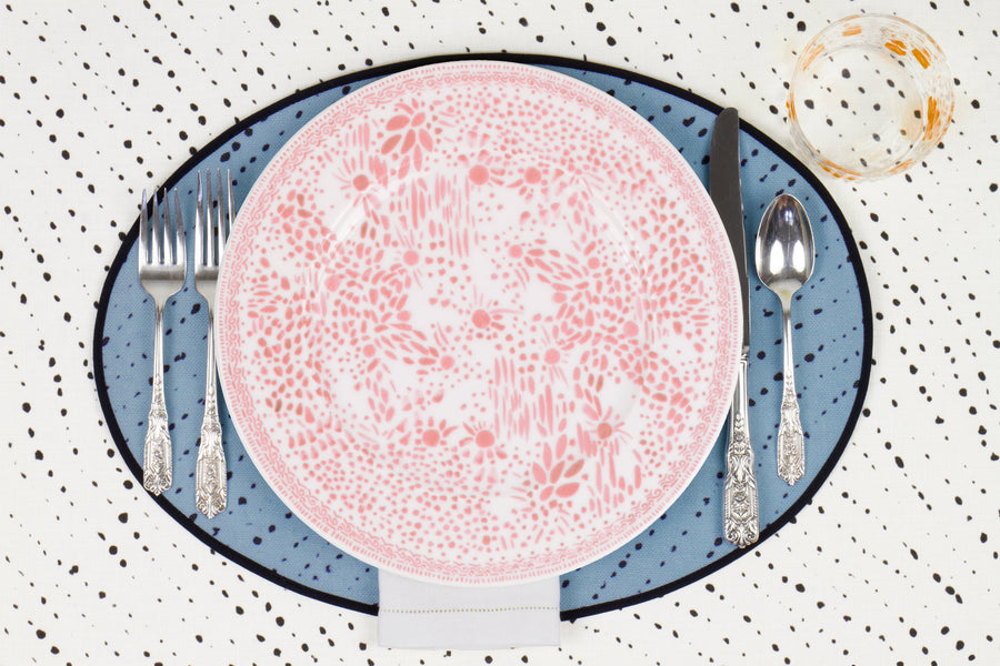 Venable Moore Mosaic Garden dinner plate in fresh grapefruit pink with hand-painted Bubble glass on sky blue 'Staccato Neroo' Shibori linen placemat and alabaster white tablecloth with silverware and white linen napkin