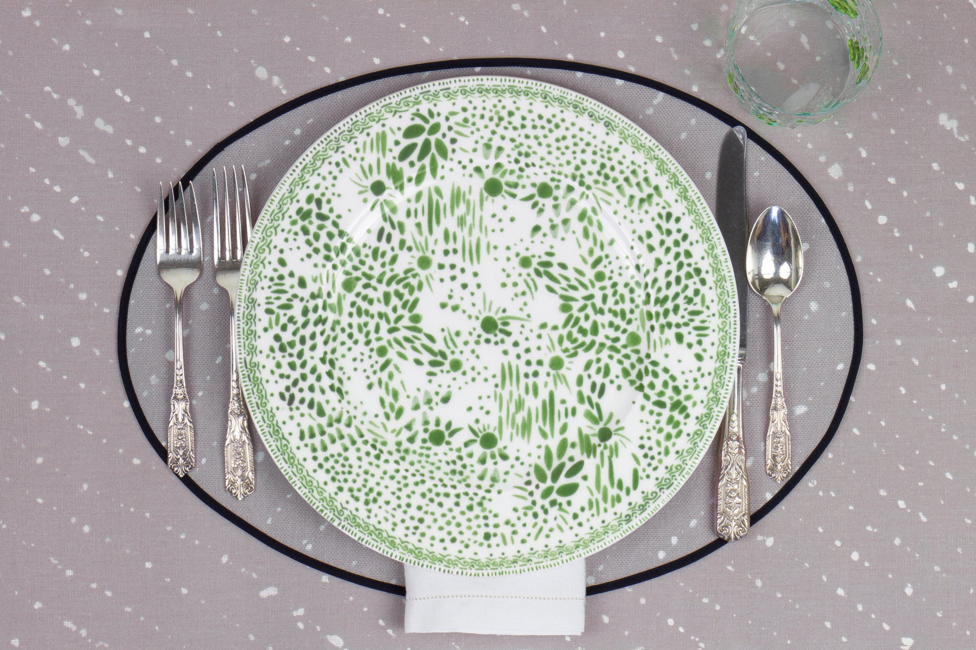 Venable Moore Mosaic Garden dinner plate in grass green with hand-painted Bubble glass on neutral flax tan 'Staccato Sbiancato' Shibori linen placemat and tablecloth with silverware and white linen napkin