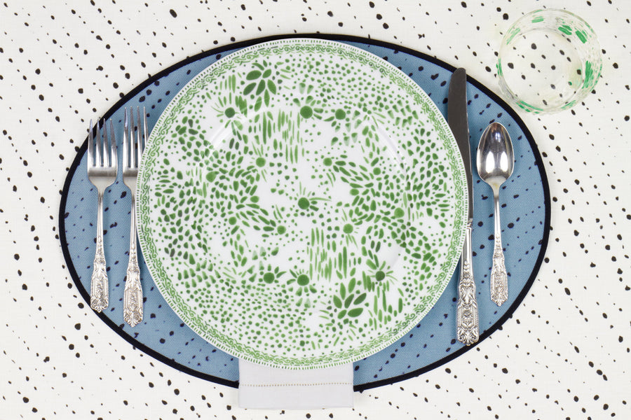 Venable Moore Mosaic Garden dinner plate in grass green with hand-painted Bubble glass on sky blue 'Staccato Neroo' Shibori linen placemat and alabaster white tablecloth with silverware and white linen napkin