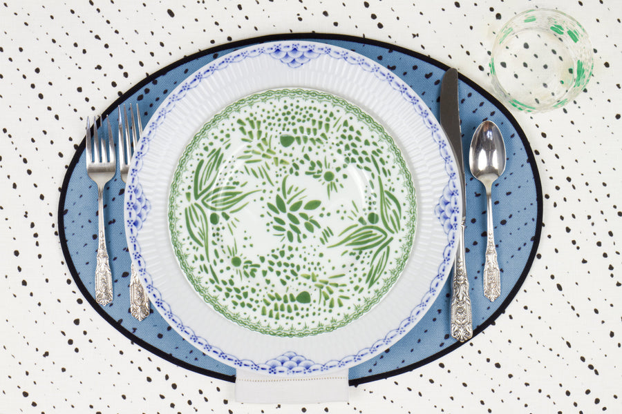Venable Moore Mosaic Garden salad/dessert plate in grass green on a blue and white plate with hand-painted Bubble glass on sky blue 'Staccato Nero' Shibori linen placemat and alabaster white tablecloth with silverware and white linen napkin