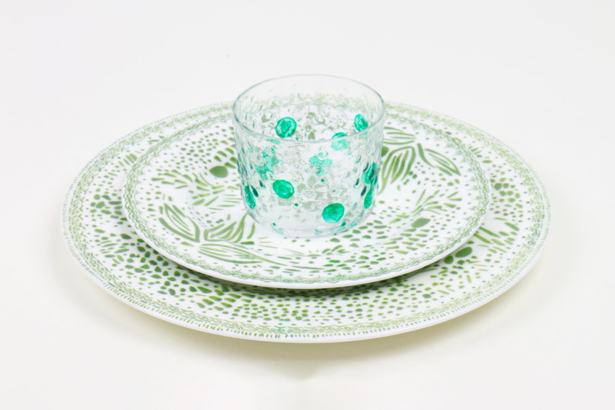 Place setting of hand-painted shamrock glass stacked on grass mosaic garden salad and dinner porcelain plates