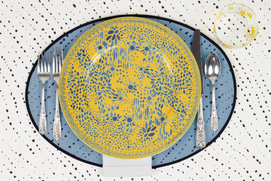 Venable Moore Mosaic Garden dinner plate in lemon yellow with hand-painted Bubble glass on sky blue 'Staccato Neroo' Shibori linen placemat and alabaster white tablecloth with silverware and white linen napkin
