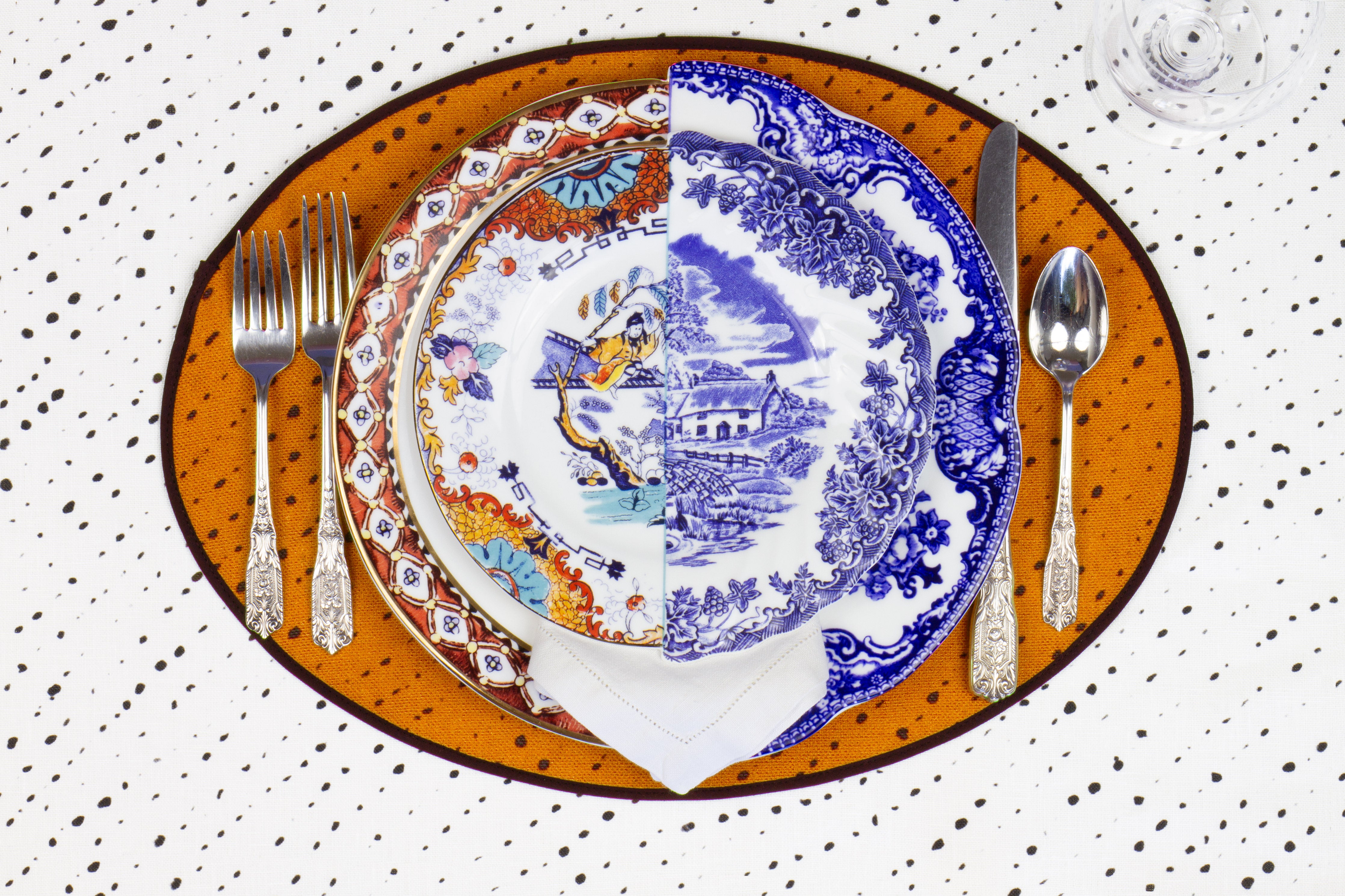 Place setting with 100% linen staccato nero shibori marigold yellow placemat on alabaster shibori with colored plates