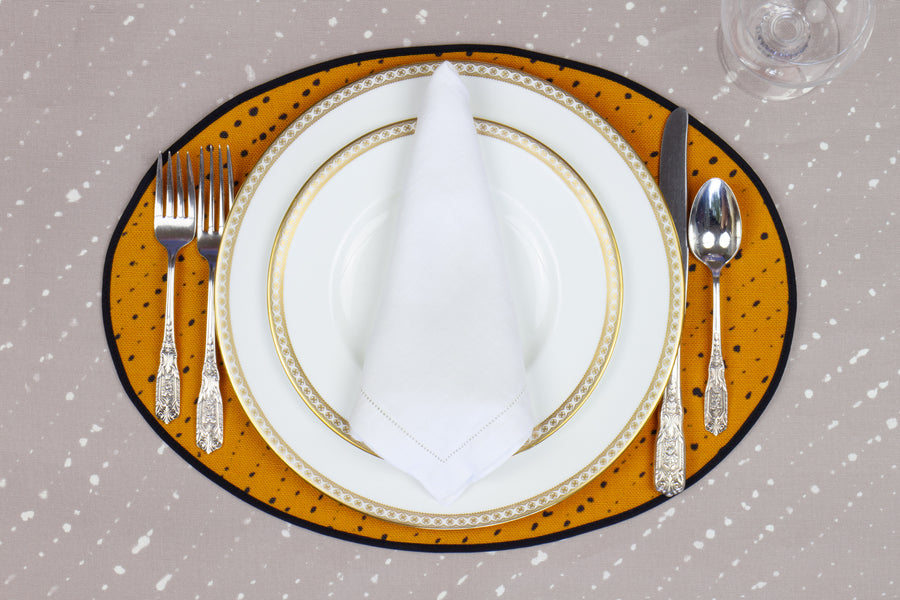 Place setting with 100% linen staccato nero marigold yellow placemat on flax shibori linen with white plates