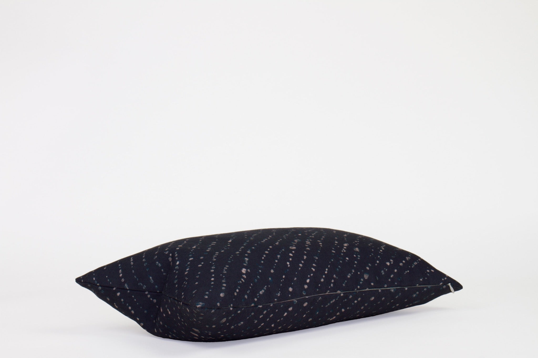 Side view 12” x 20” 100% linen staccato decolorato shibori pillow in midnight blue with hidden zipper