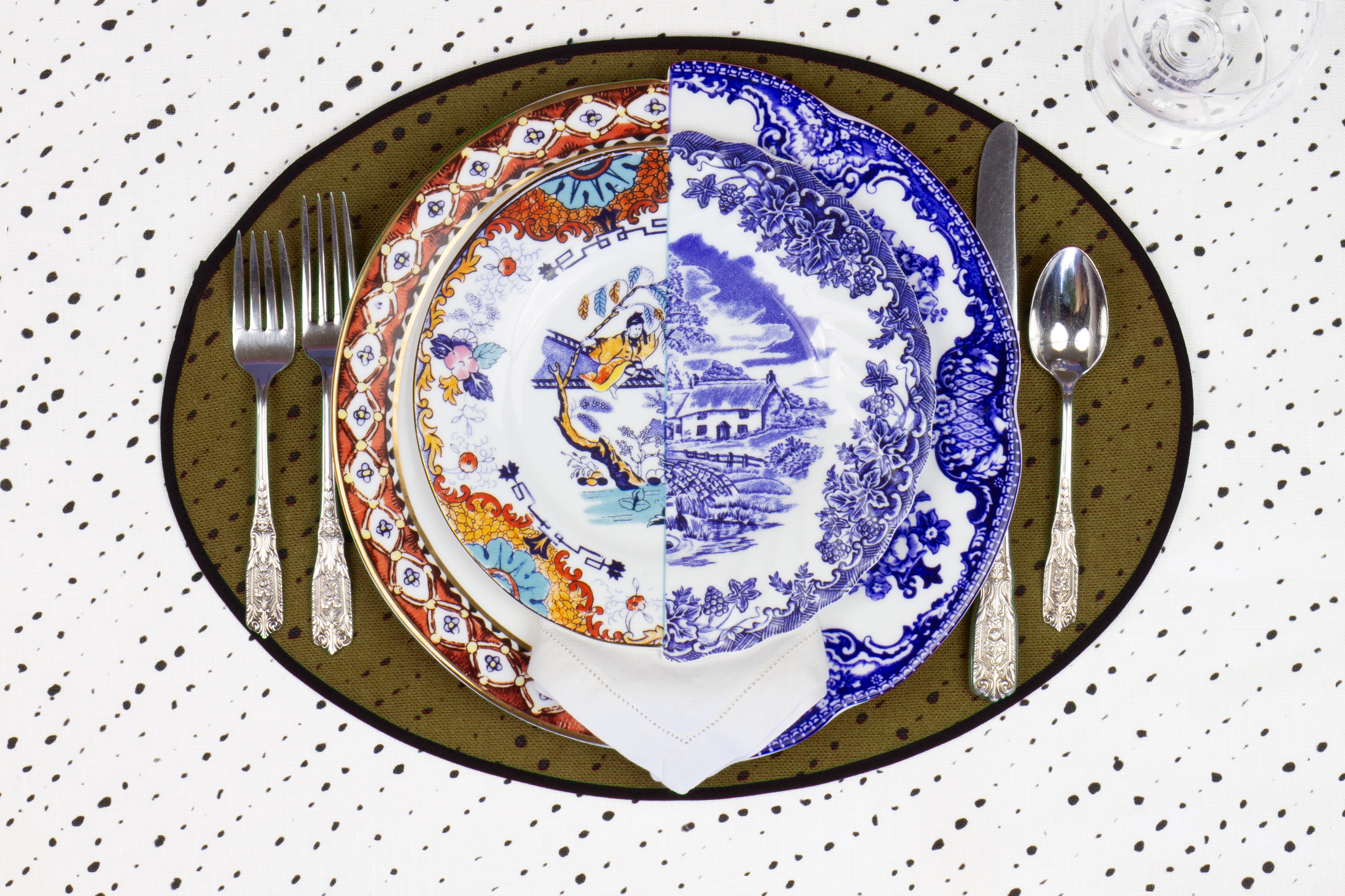 Place setting with 100% linen staccato nero shibori moss green placemat on alabaster shibori with colored plates