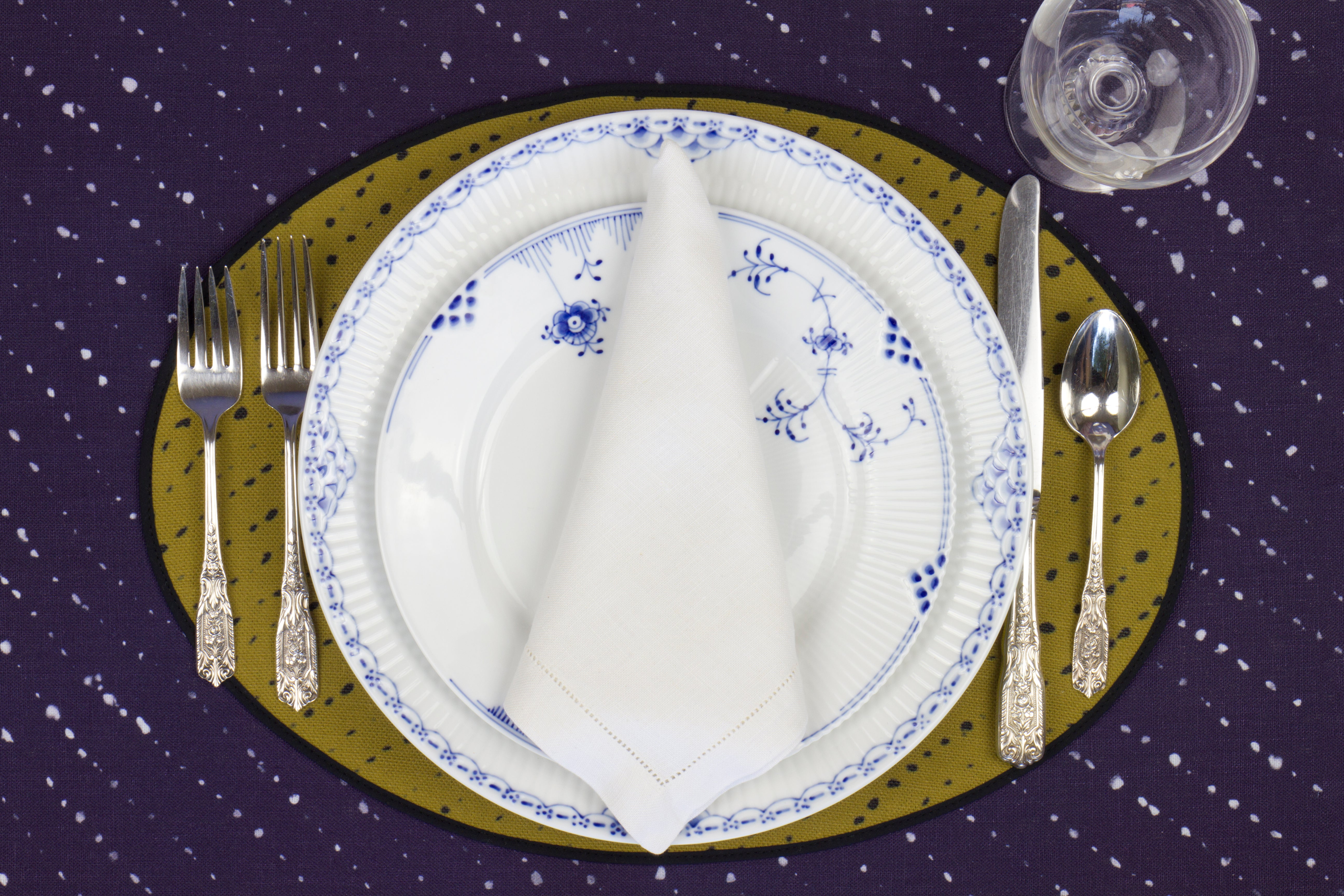 Place setting with 100% linen staccato nero shibori moss green placemat on linen with blue & white plates