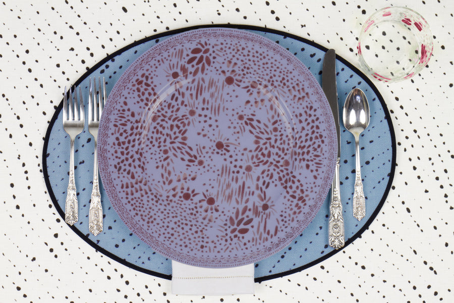 Venable Moore Mosaic Garden dinner plate in soft myrtle purple with hand-painted Bubble glass on sky blue 'Staccato Neroo' Shibori linen placemat and alabaster white tablecloth with silverware and white linen napkin