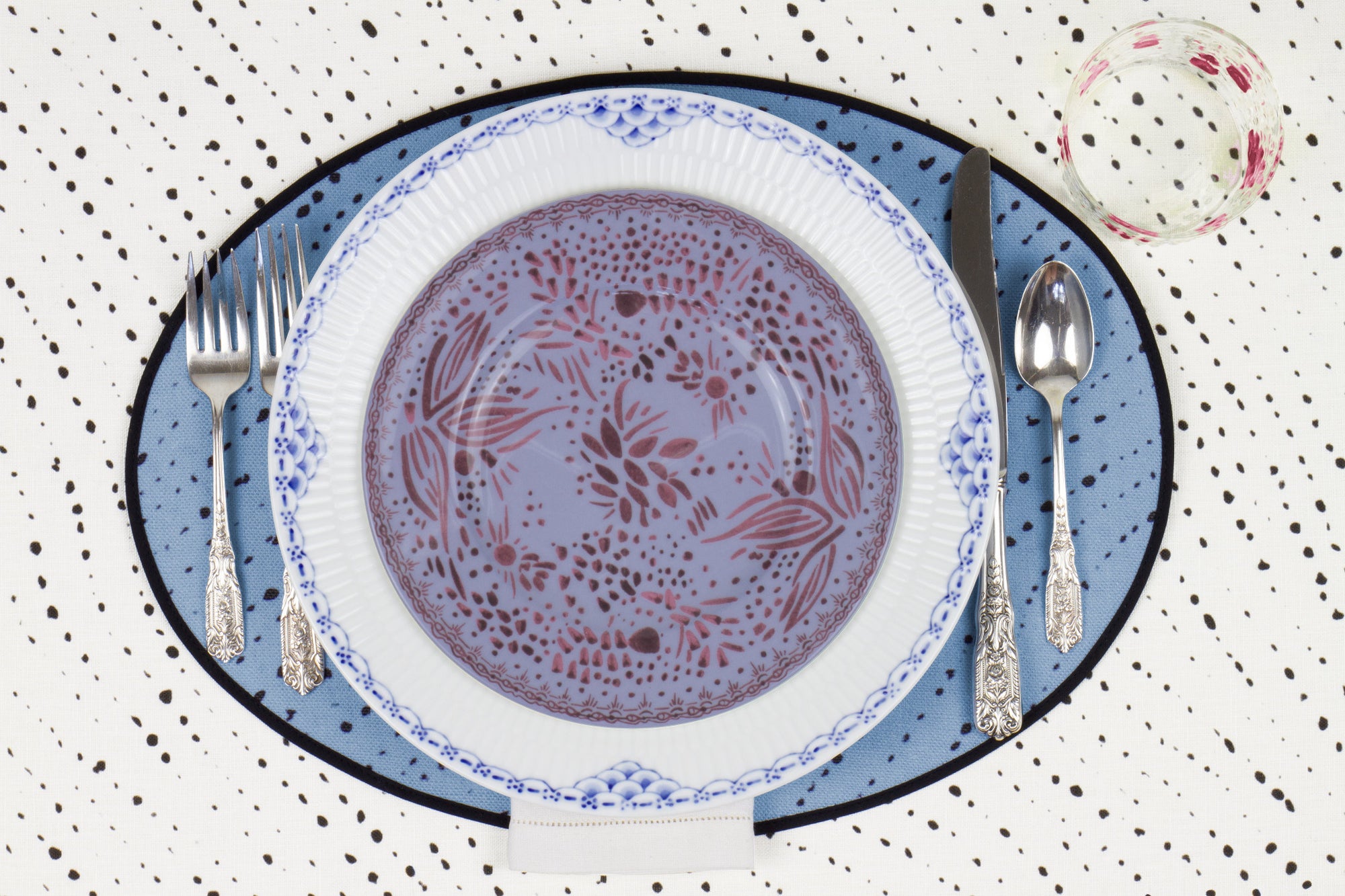 Venable Moore Mosaic Garden salad/dessert plate in soft myrtle purple on a  blue and white plate with hand-painted Bubble glass on sky blue 'Staccato Nero' Shibori linen placemat and alabaster white tablecloth with silverware and white linen napkin