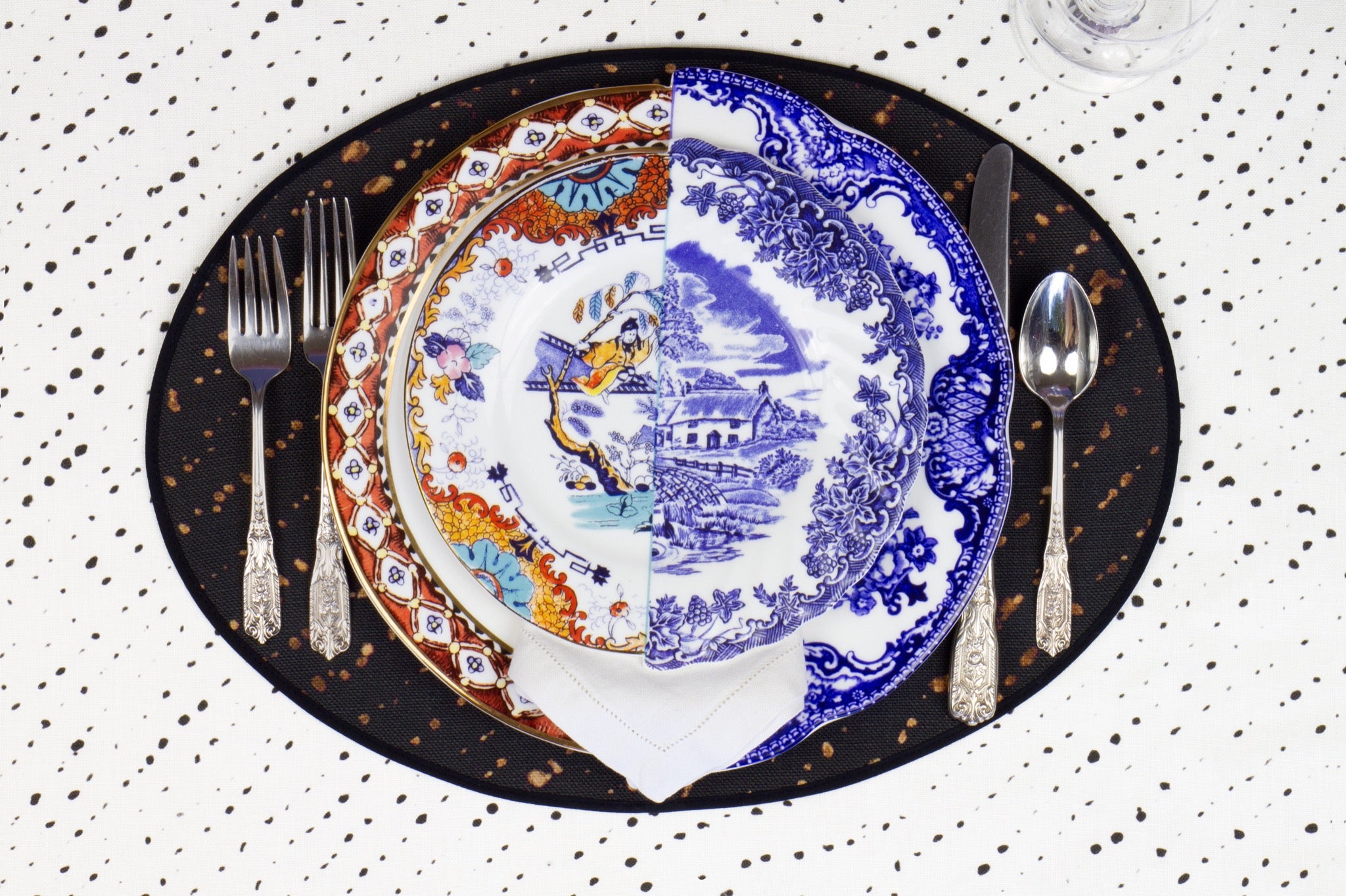 Place setting with 100% linen staccato decolorato shibori onyx black placemat on alabaster shibori with colored plates