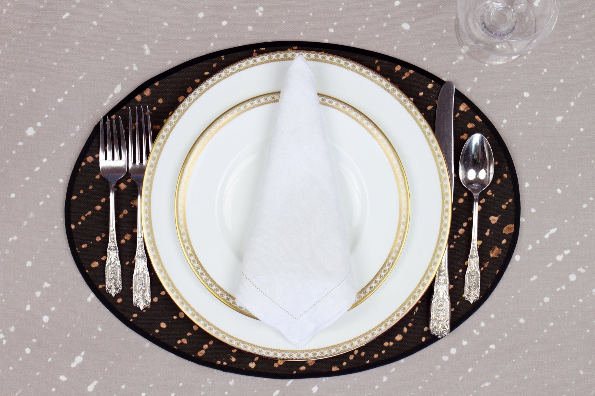 Place setting with 100% linen staccato decolorato onyx black placemat on flax shibori linen with white plates