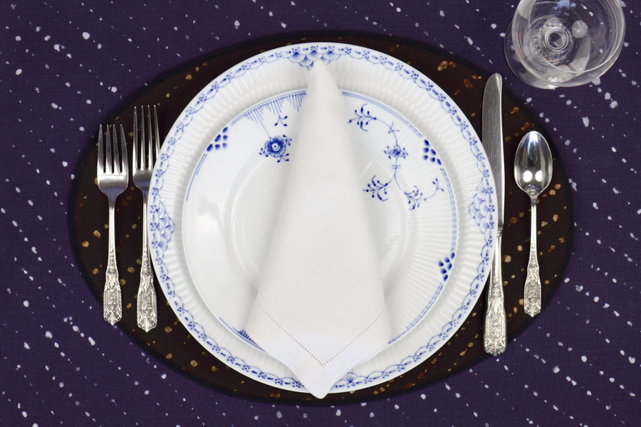 Place setting with 100% linen staccato decolorato shibori onyx black placemat on linen with blue & white plates