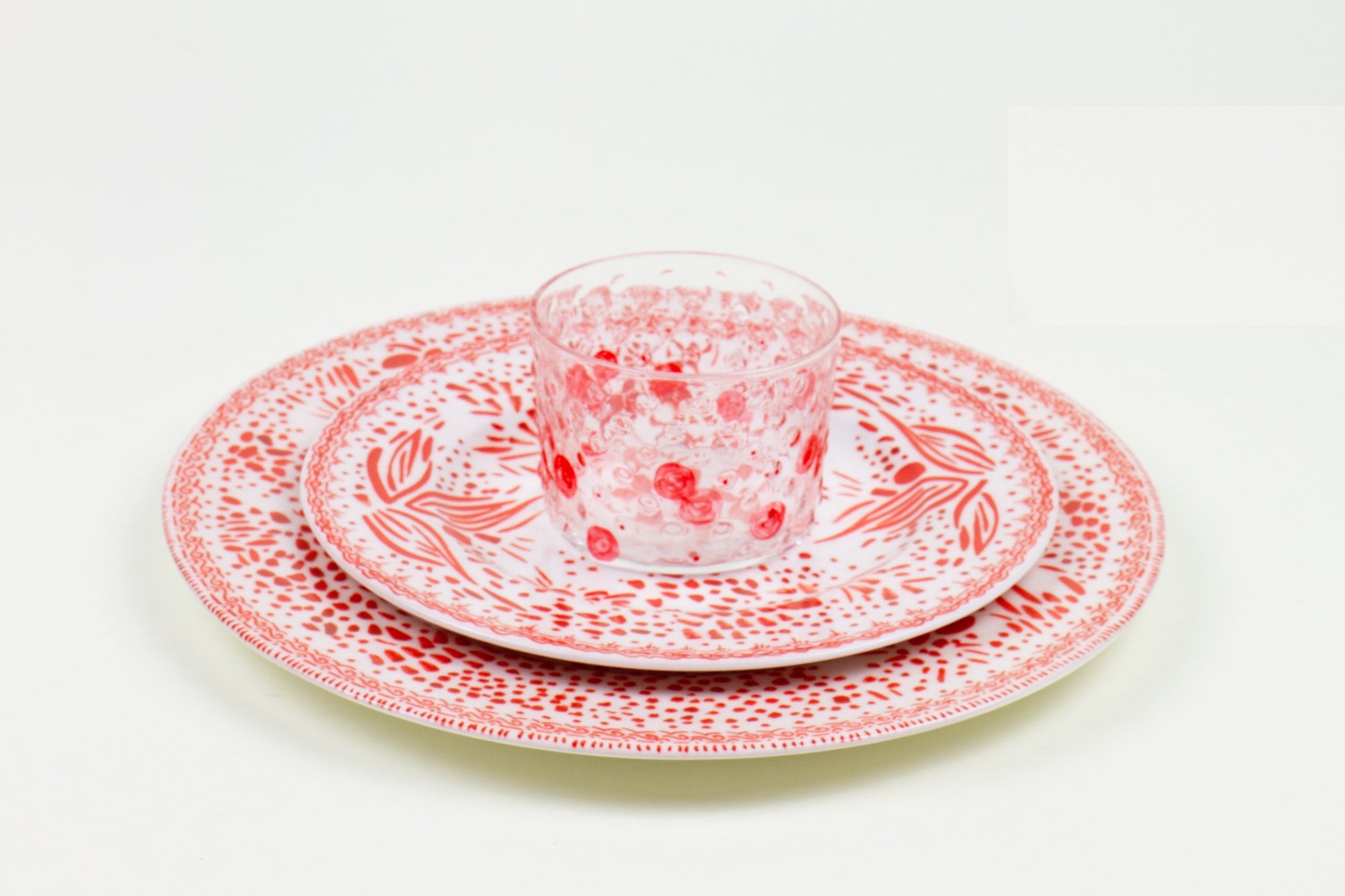 Place setting of hand-painted tomato glass stacked on pale orchid mosaic garden salad and dinner porcelain plates