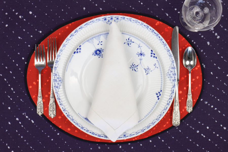 Place setting with 100% linen staccato decolorato shibori paprika red placemat on linen with blue & white plates