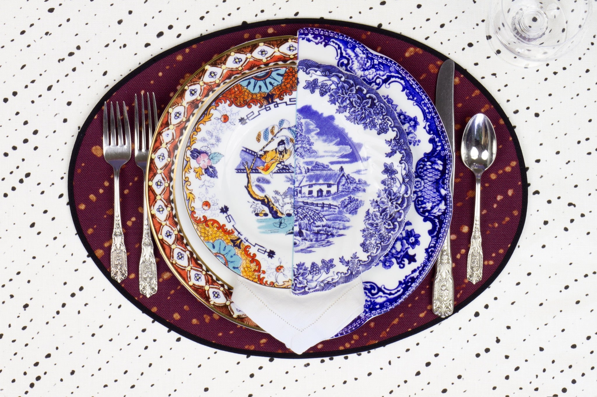 Place setting with 100% linen staccato decolorato shibori plum purple placemat on alabaster shibori with colored plates