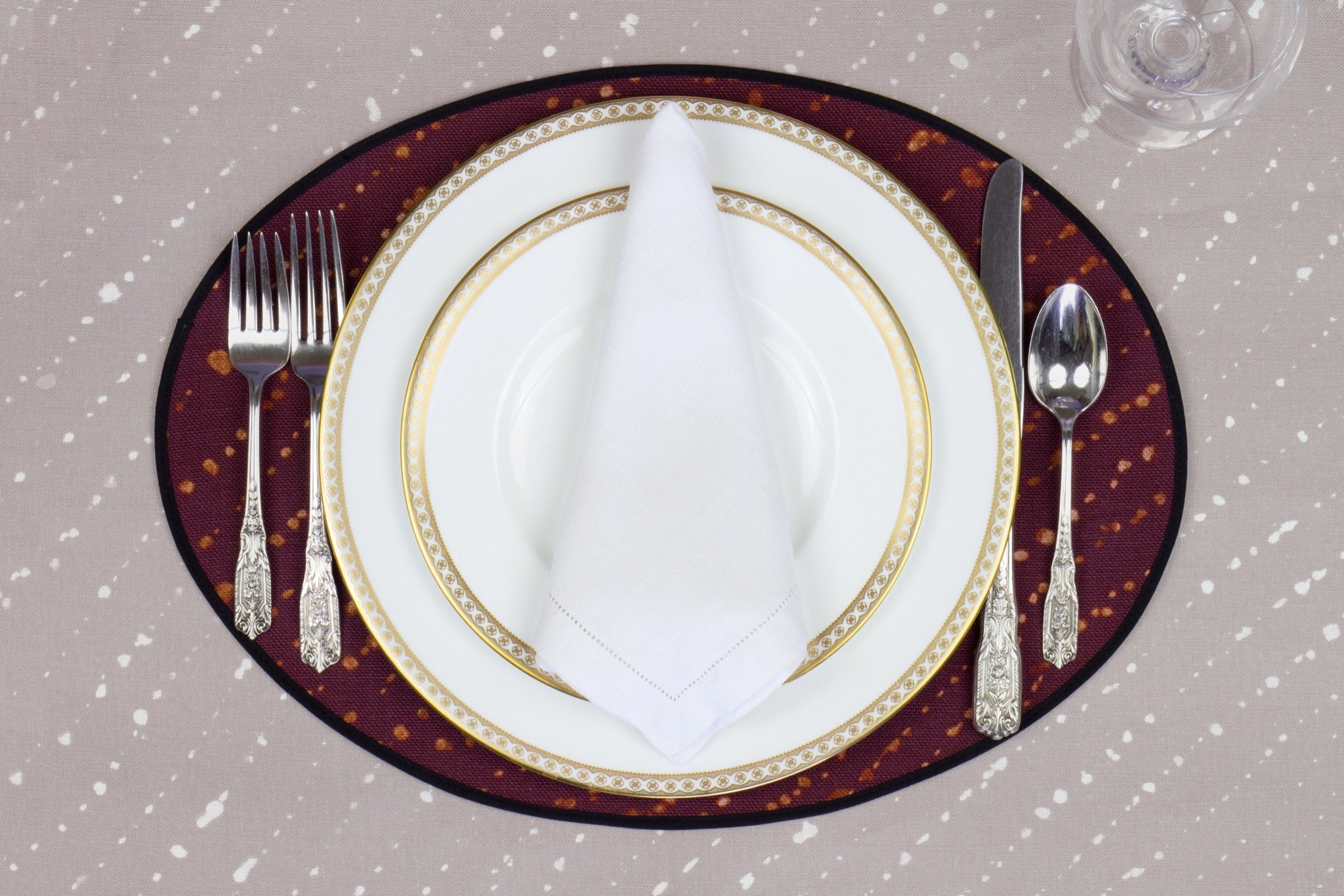 Place setting with 100% linen staccato decolorato shibori plum purple placemat on flax shibori linen with white plates