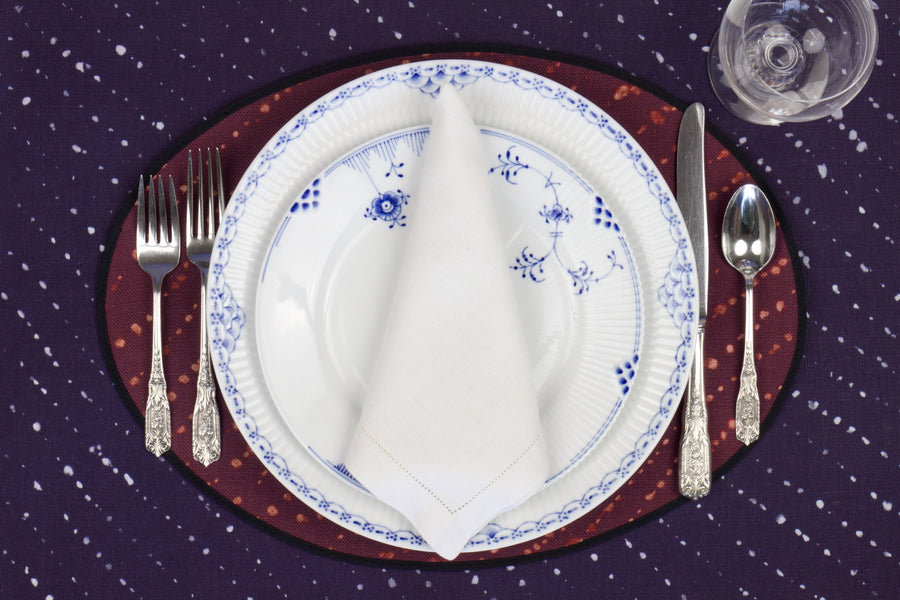 Place setting with 100% linen staccato decolorato shibori plum purple placemat on linen with blue & white plates