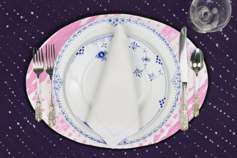Place setting with 100% linen glissando shibori posy pink placemat on sapphire linen with blue & white plates