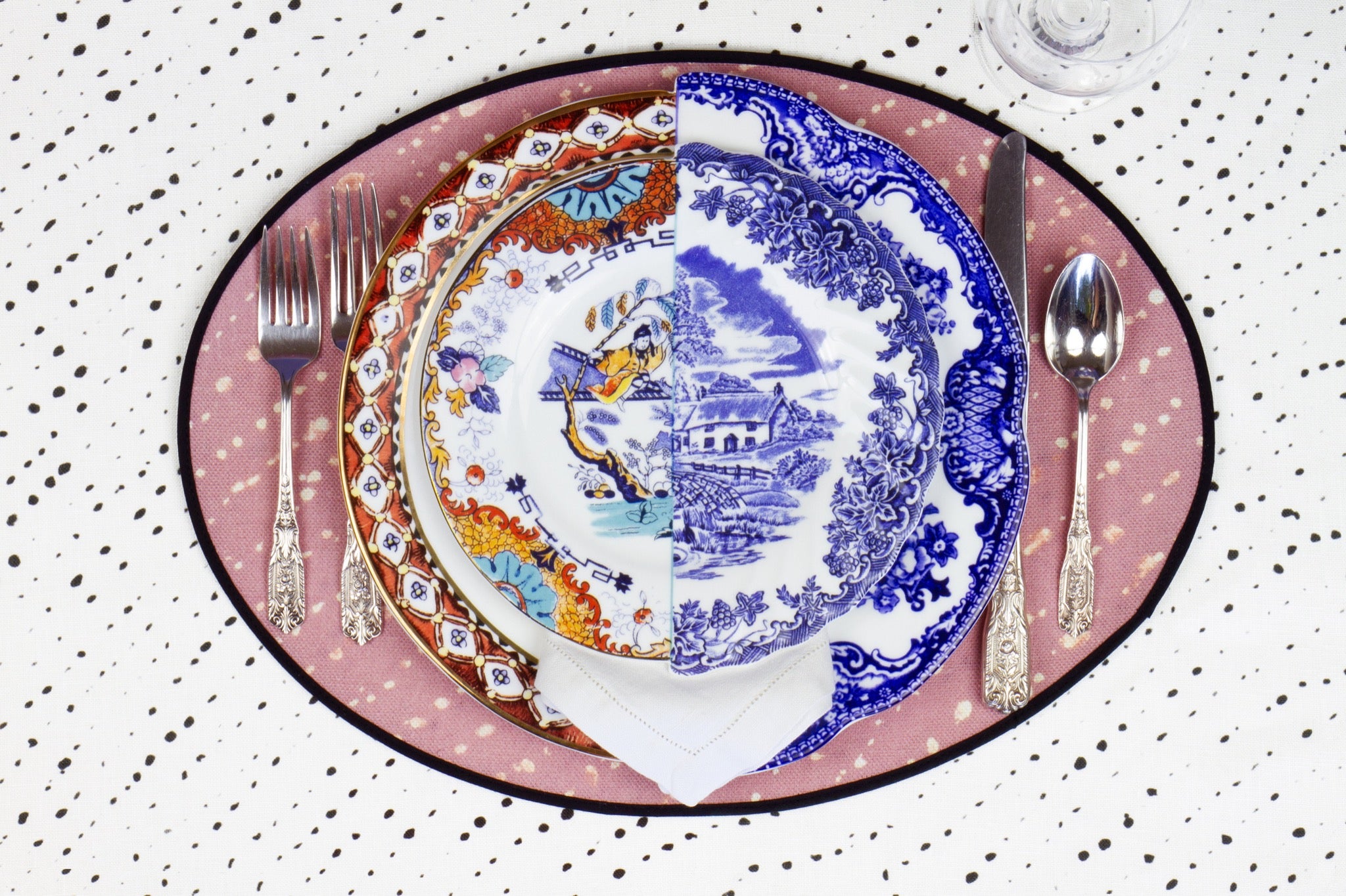 Place setting with 100% linen staccato decolorato shibori rose clay pink placemat on alabaster shibori with colored plates