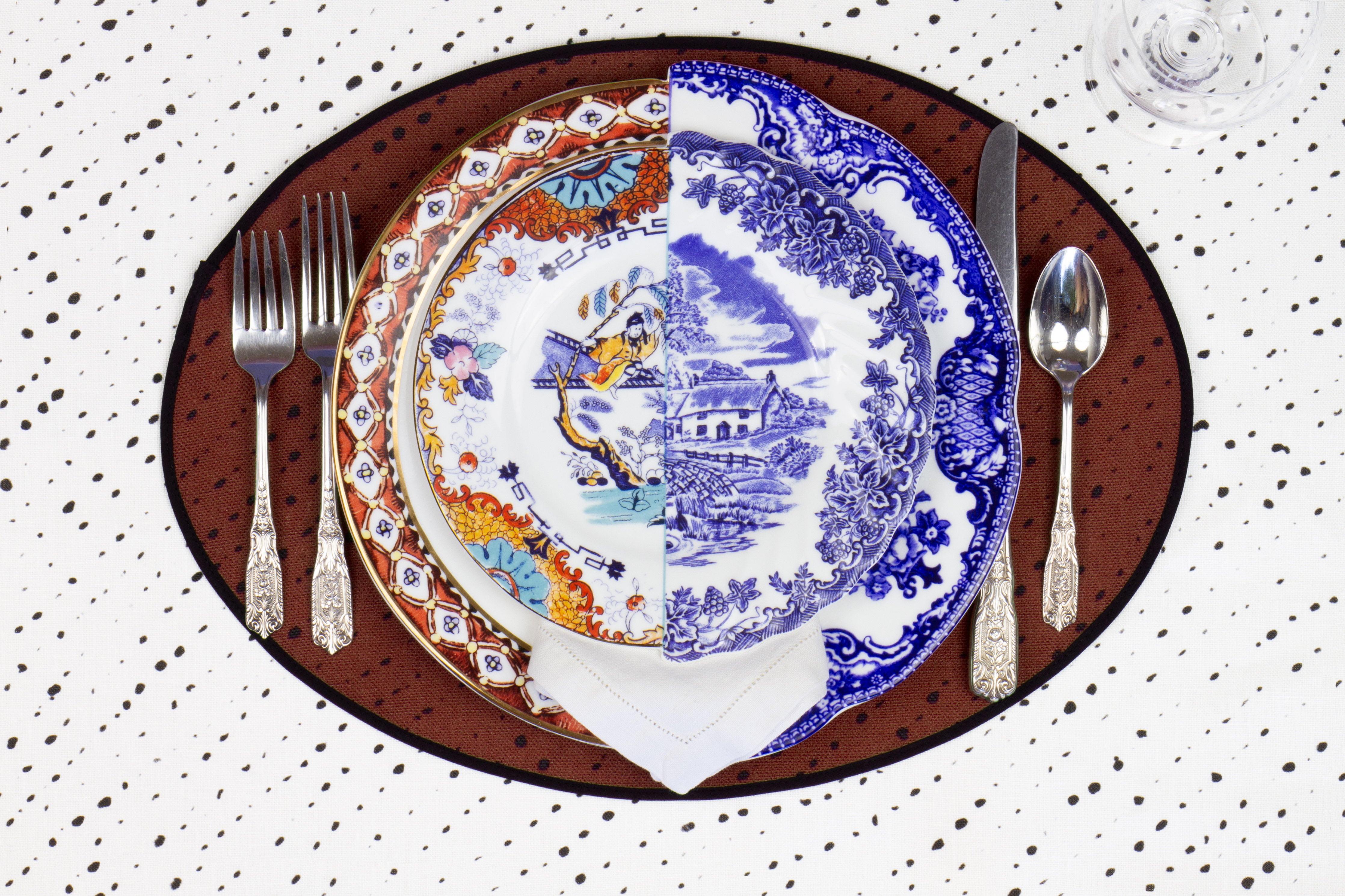 Place setting with 100% linen staccato nero shibori prusset brown placemat on alabaster shibori with colored plates