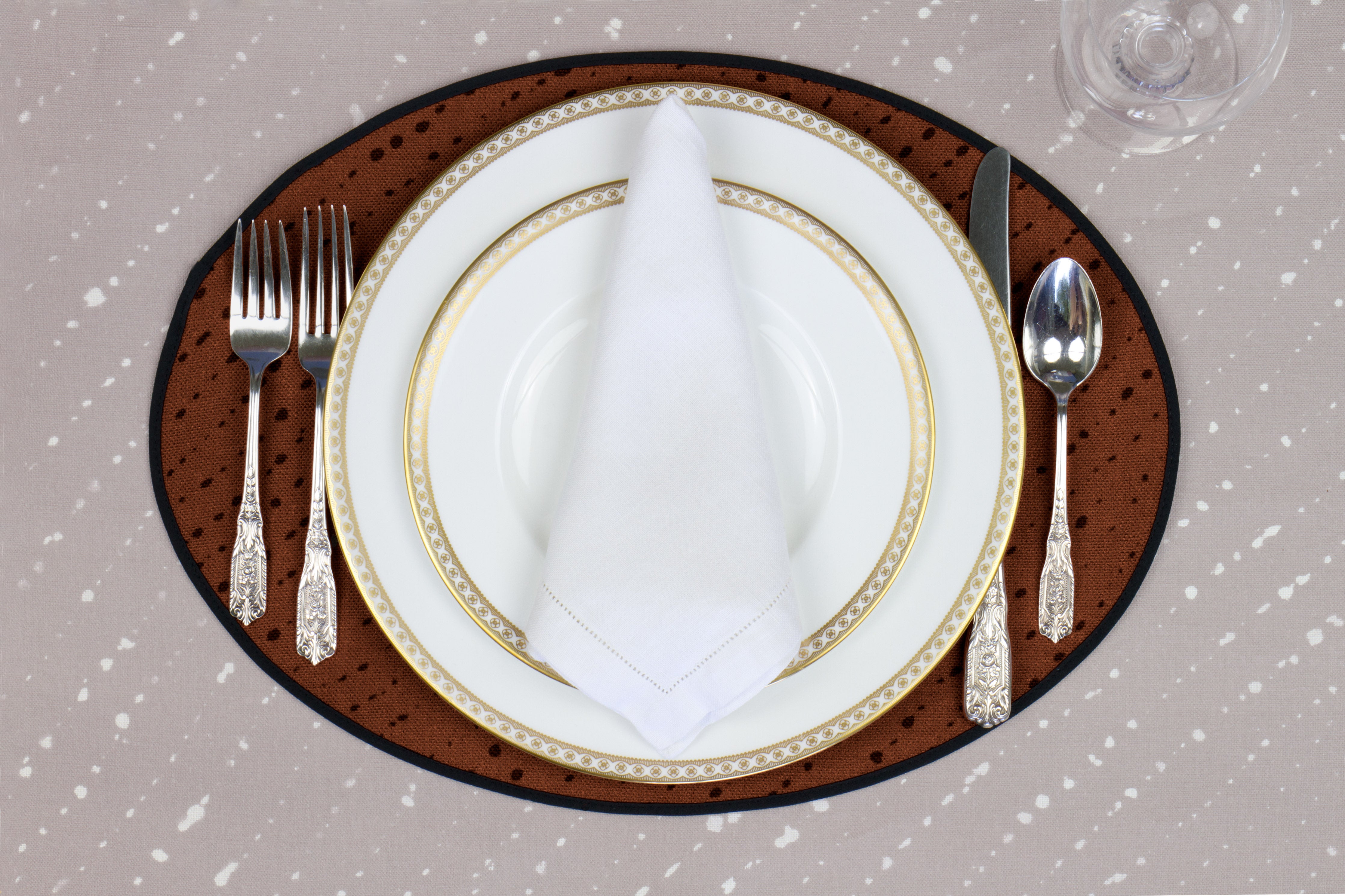 Place setting with 100% linen staccato nero shibori russet brown placemat on flax shibori linen with white plates