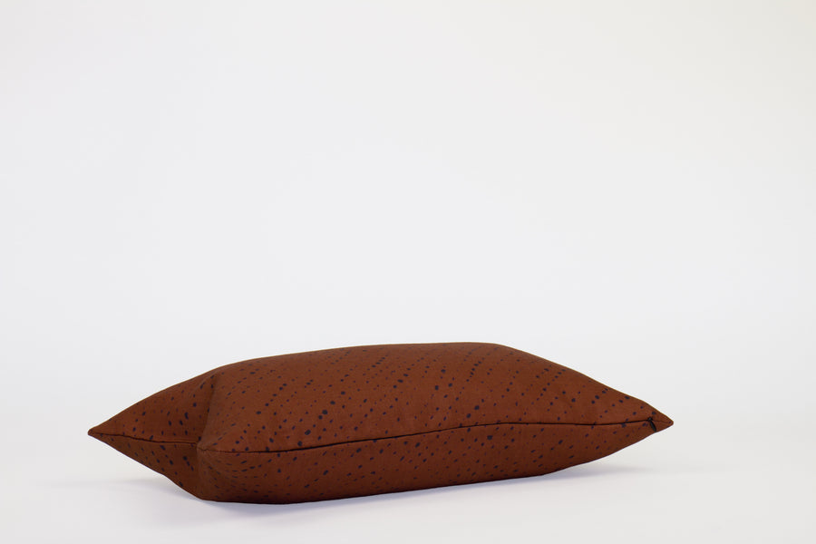 Side view 12” x 20” 100% linen staccato nero shibori pillow in russet brown with hidden zipper