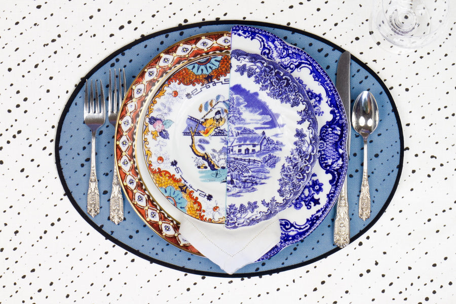 Place setting with 100% linen staccato nero shibori sky blue placemat on alabaster shibori with colored plates