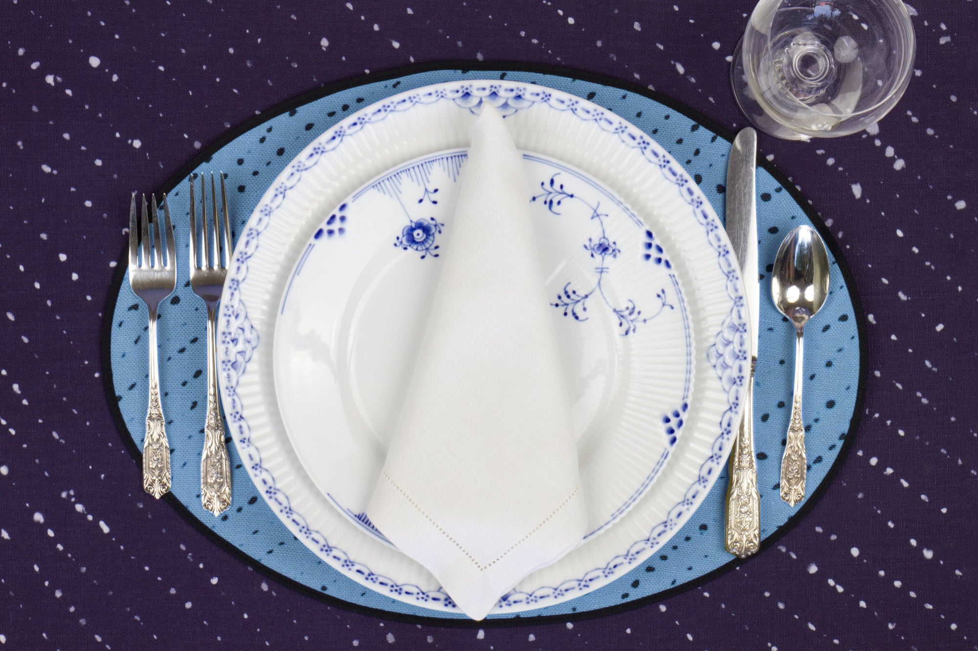 Place setting with 100% linen staccato nero shibori sky blue placemat on linen with blue &amp; white plates