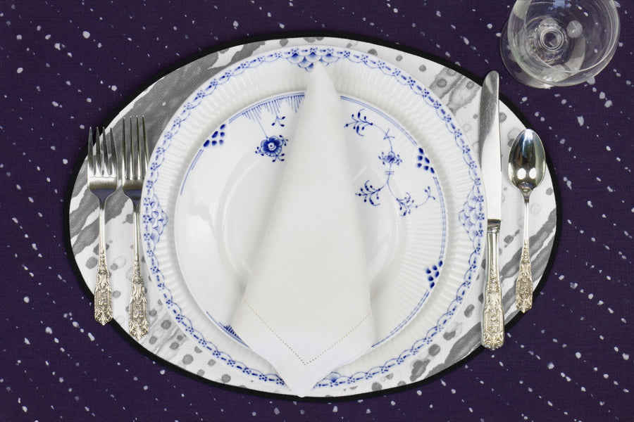 Place setting with 100% linen glissando shibori storm grey placemat on sapphire linen with blue & white plates