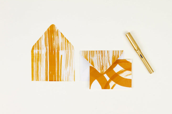 Hand-painted card and crimson lined envelopes in ochre in ‘stripes and squiggles’ pattern with gold pen